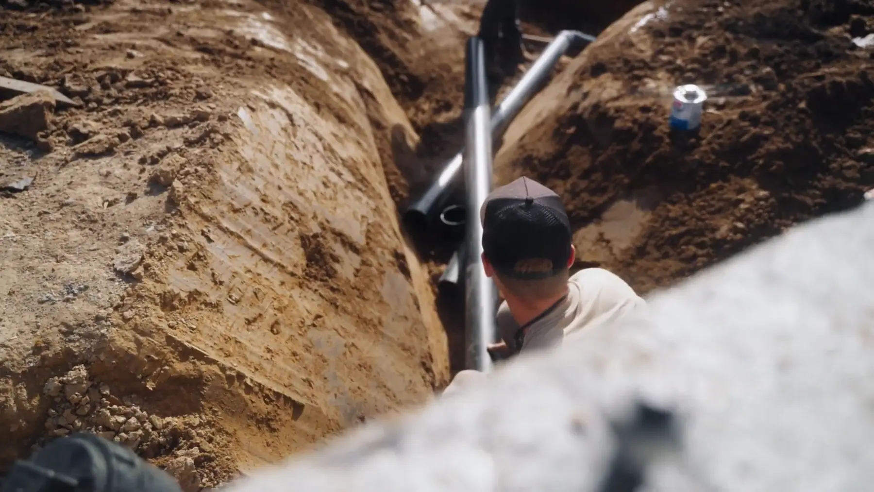 LPG crew member laying pipe in an open trench