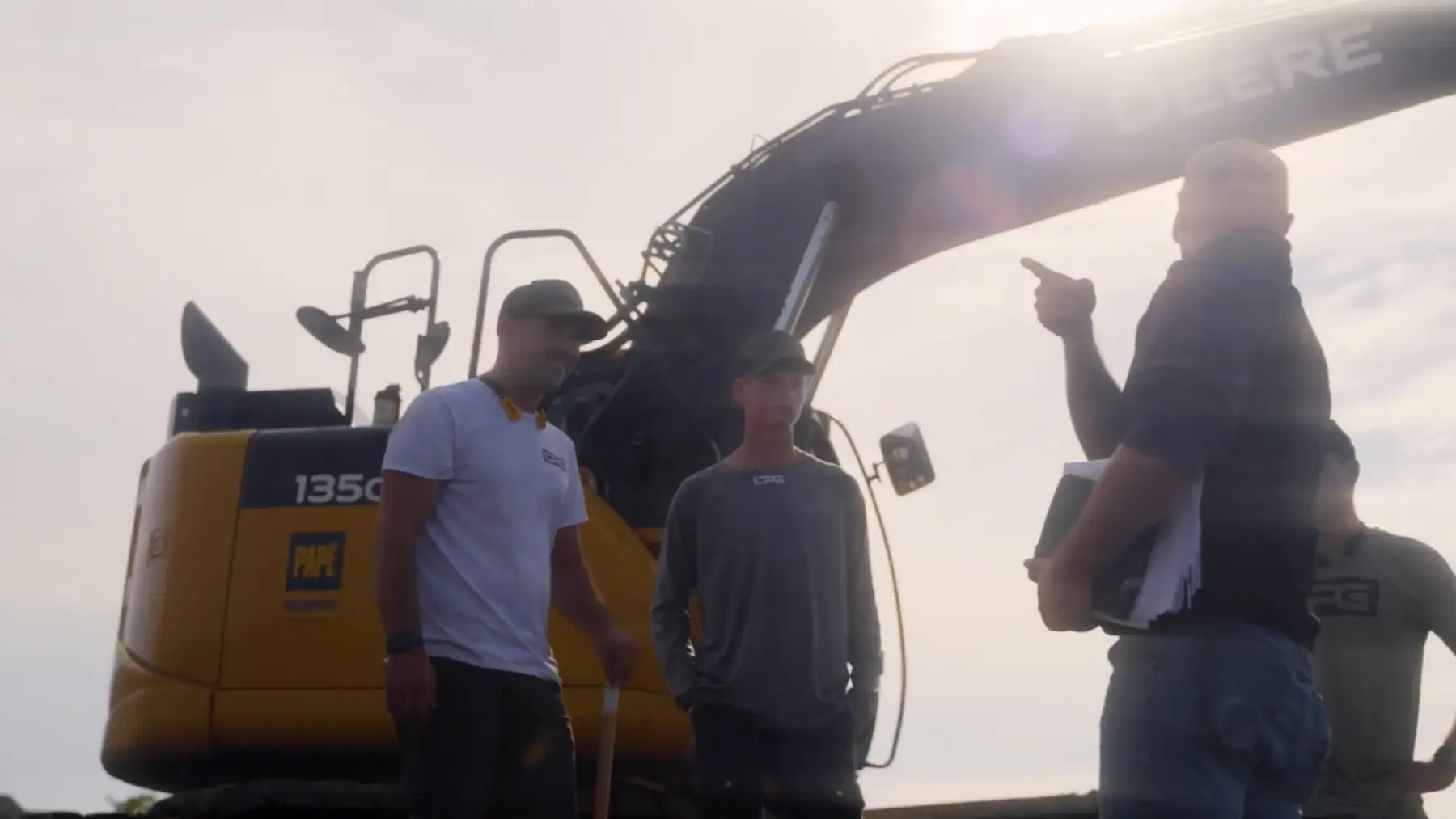 LPG crew going over the plan beside a Deere excavator
