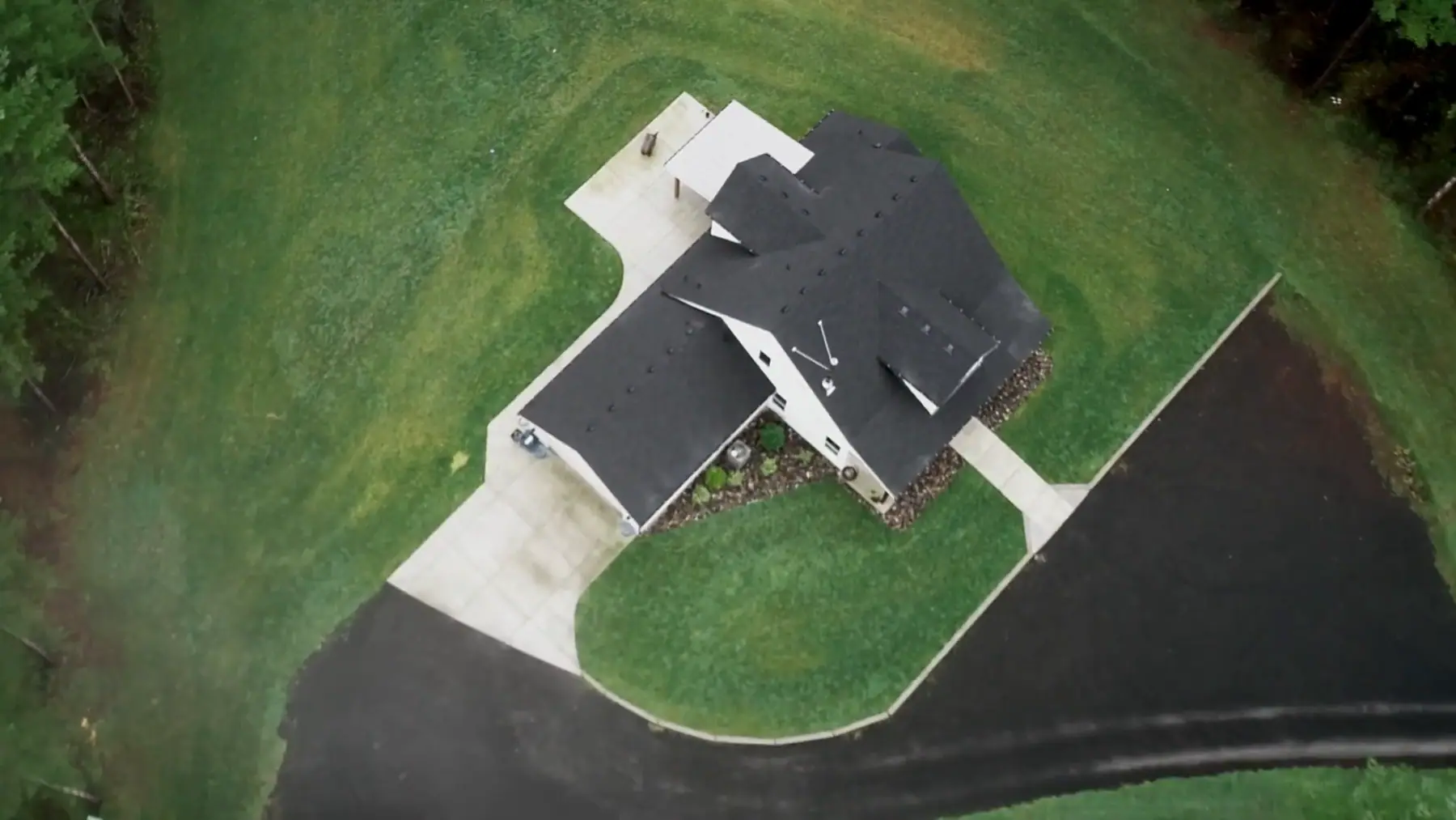 Aerial view of a finished home and driveway on a large lot
