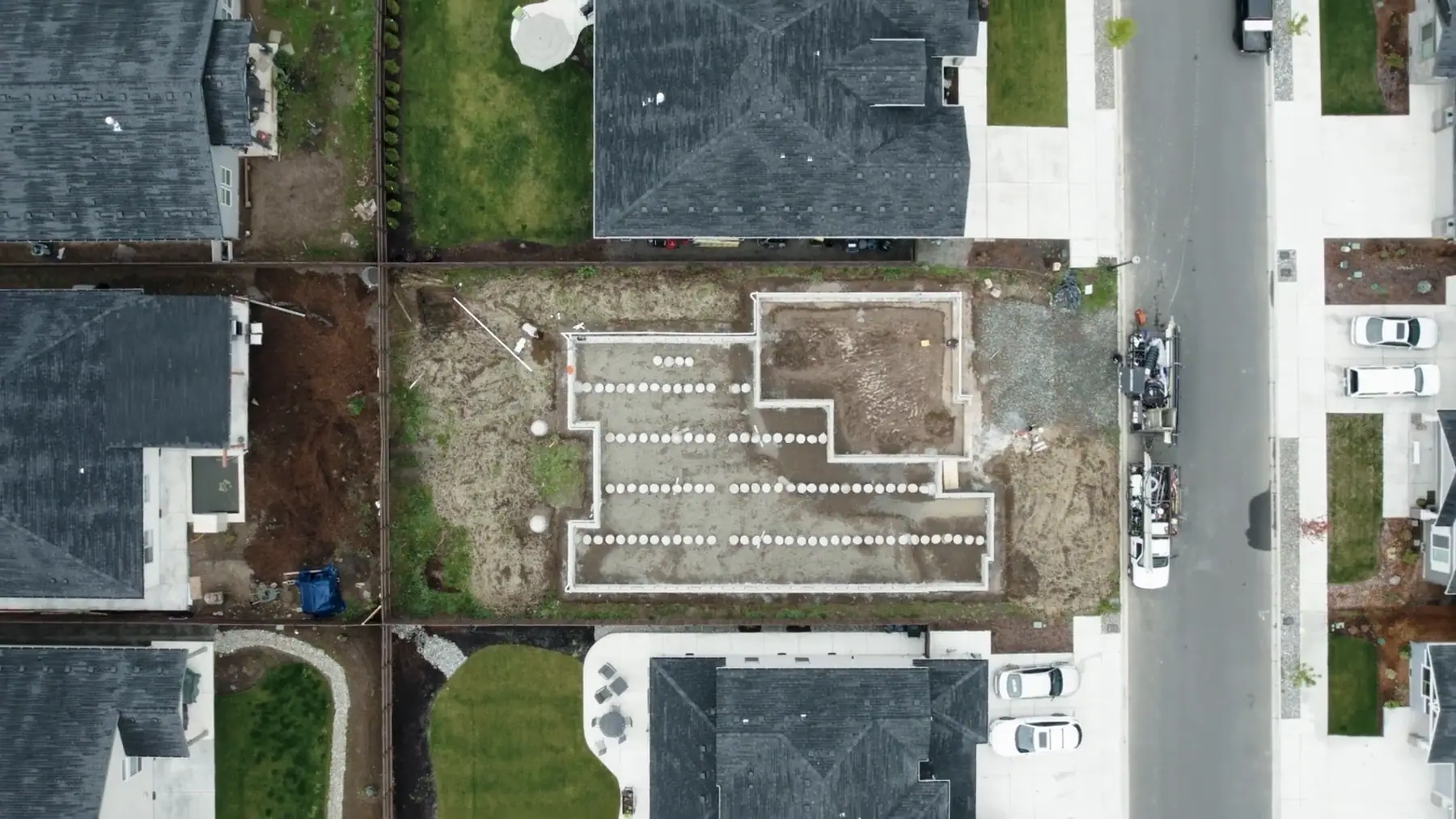 Aerial view of a foundation going in on a production lot between finished homes