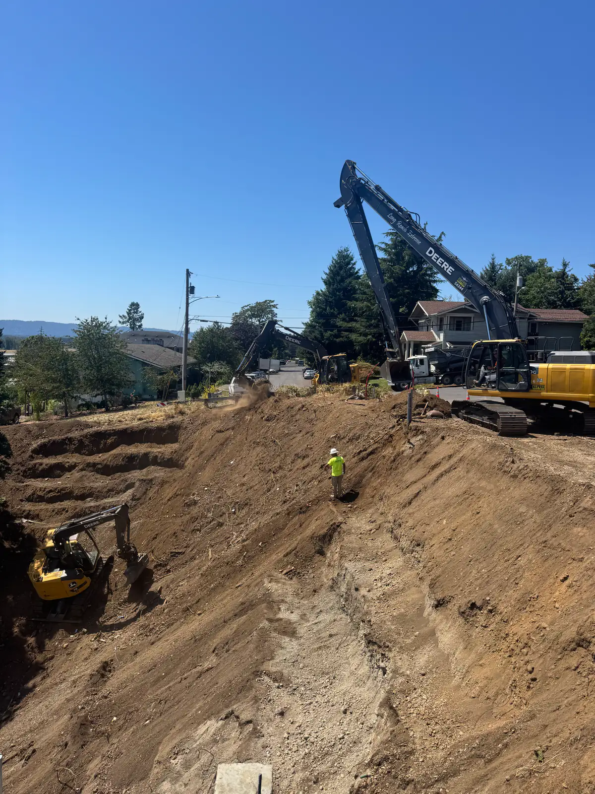Long-reach excavator and LPG crew working a deep cut on a tight site